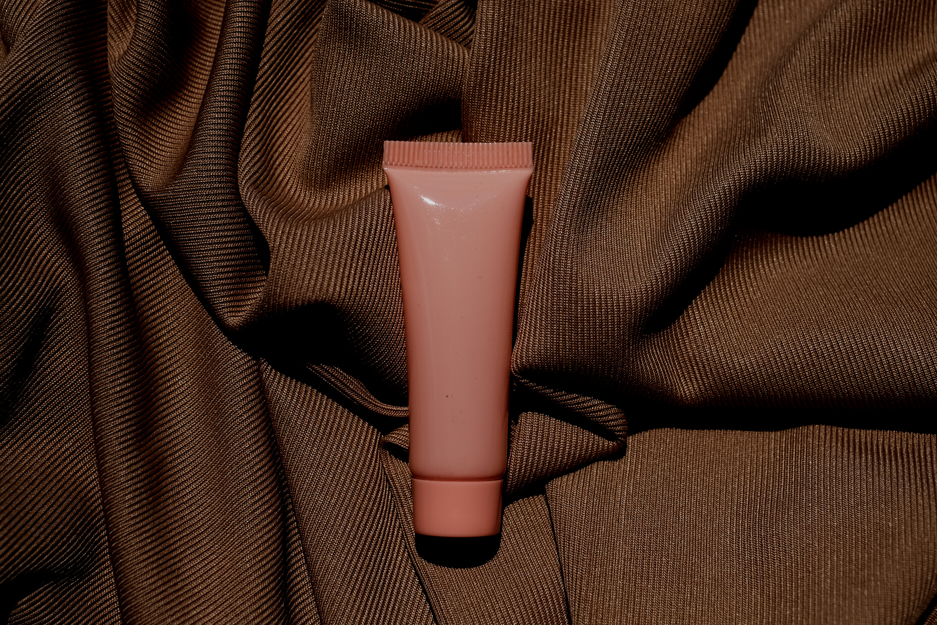 Pink Cosmetic Tube on Brown Fabric